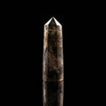 A moody, dark aesthetic studio shot of the Somna Aura Smokey Quartz Point. The single-terminated hexagonal crystal stands upright against a stark background, showcasing its deep, smoky translucent hues—the ultimate sanctuary piece for energetic boundaries and grounding.